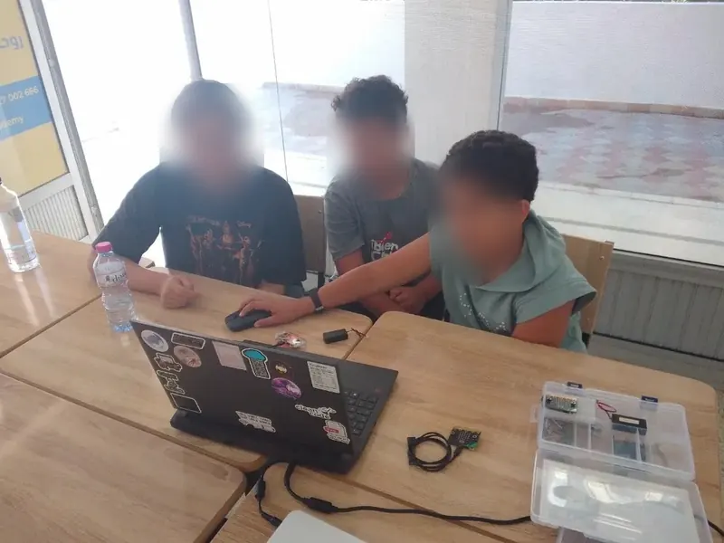 Trois élèves programment leur robot ensemble